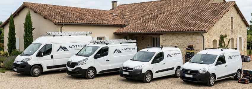 Les fourgons logotés Altys Toiture alignés devant une maison girondine en tuile canal